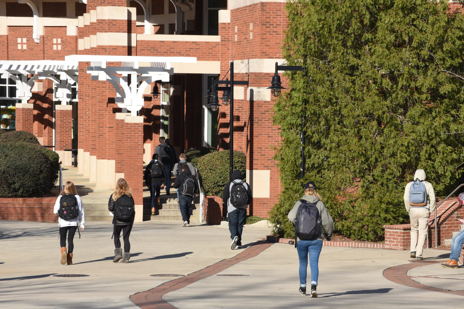 Students walking with backpacks into a college campus.