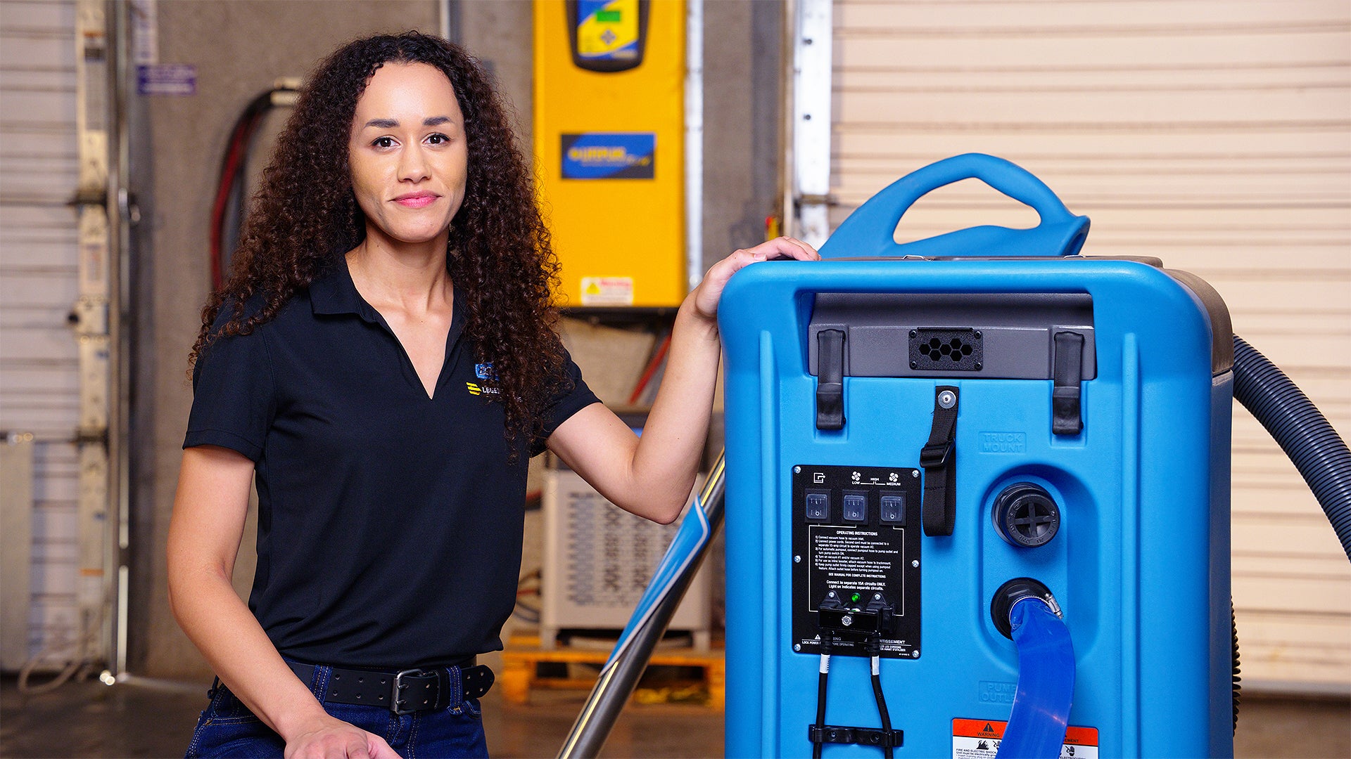 Woman with R2R logo branded polo shirt next to a dehumidifier showing the back of it